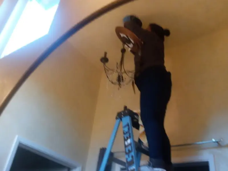 Electrician installing a chandelier in a Kelly residence